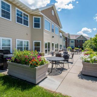 A sunny outdoor patio area featuring comfortable seating and vibrant flower planters, perfect for relaxation.