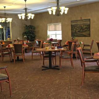 An empty dining room with neatly arranged tables and chairs, featuring warm lighting and wall decorations.