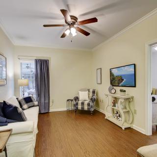 A cozy living room with a ceiling fan, comfortable couch, and a mounted television.