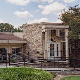 A modern stone-faced building with a ramp and an inviting entrance.