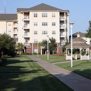 A residential apartment building with a well-maintained grassy area and a gazebo.