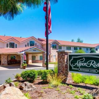 Entrance of Aspen Ridge with a welcome sign and well-maintained landscaping on a sunny day.