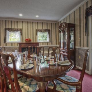 A traditional dining room with a wooden table and chairs, elegantly set for a meal.