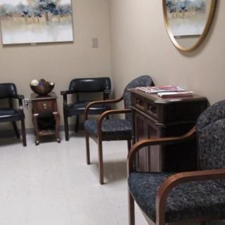 A waiting room with chairs, wall art, and a mirror.
