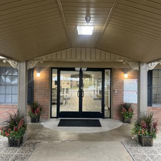 The inviting entrance of a building, featuring warm lighting and flower arrangements.
