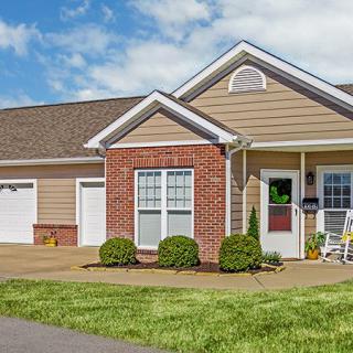 A suburban residential house with a brick facade, garage, and well-maintained front yard.