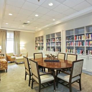 A cozy library interior with bookshelves, a round table, and chairs for reading or meetings.