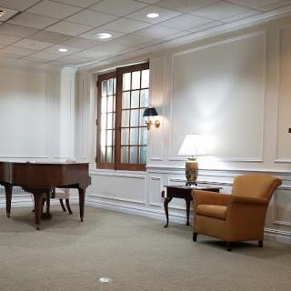A serene room featuring a piano, an armchair, and soft lighting.