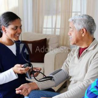 A nurse taking an elderly patient's blood pressure during a home visit.