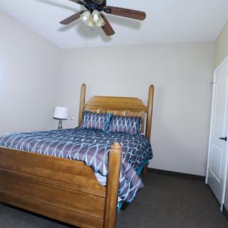 A cozy bedroom featuring a wooden bed with patterned bedding and a ceiling fan.