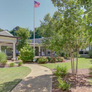 A landscaped garden with a pathway leading to a building, featuring a flagpole.