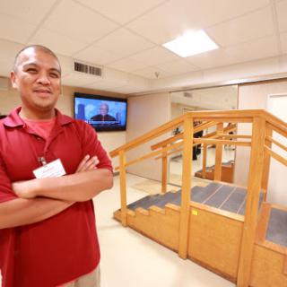 A healthcare professional stands confidently in a rehabilitation facility, highlighting the supportive environment for physical therapy.