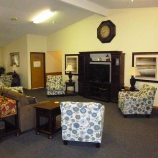 A cozy living room with patterned chairs, a sofa, and a TV entertainment center.