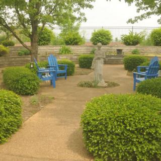 A tranquil garden with blue chairs and neatly trimmed bushes, creating a peaceful outdoor setting.