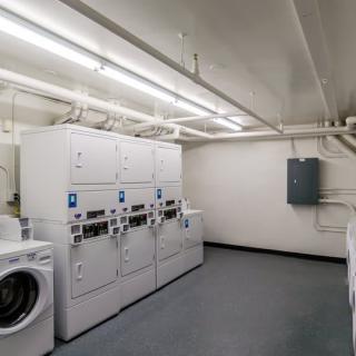 A clean and well-organized laundry room with multiple washing machines and dryers.