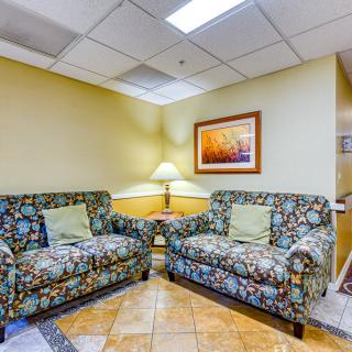 A cozy lobby seating area with patterned couches and a lamp providing warm lighting.
