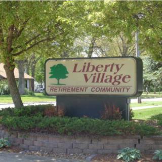 Sign for Liberty Village Retirement Community surrounded by trees.