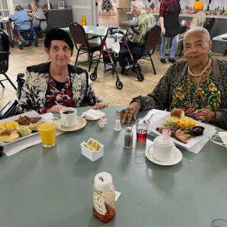 Two friends enjoying a meal together at a community dining area.