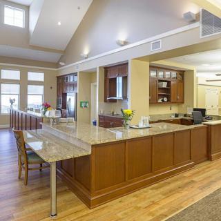 A modern kitchen with an island countertop and wooden cabinets, featuring bright lighting and an open layout.