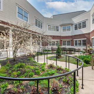 A courtyard featuring a garden with pathways and railings surrounded by a multi-story building.