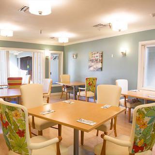 A modern dining room with neatly arranged tables and chairs, featuring bright lighting and colorful decor.