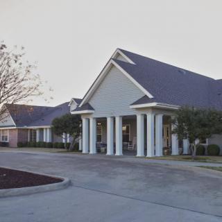 A view of a healthcare clinic with a prominent entrance and surrounding parking area.