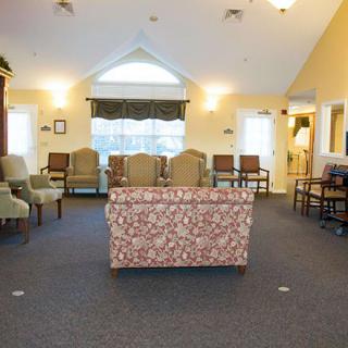 A cozy waiting room featuring an array of chairs and a patterned sofa, with large windows bringing in natural light.
