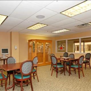 A well-lit office room featuring multiple tables and chairs with a carpeted floor.