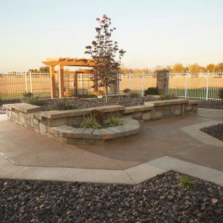 A serene garden with a pergola, stone seating, and pathways.