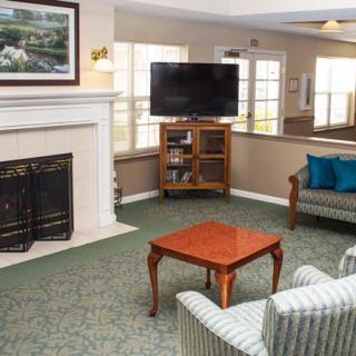 A cozy living room with a fireplace and television, featuring comfortable seating and elegant decor.
