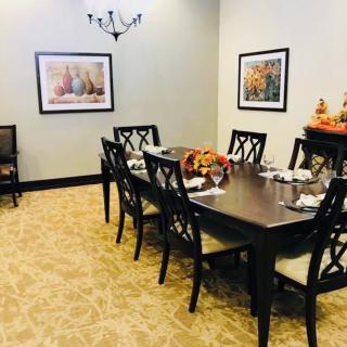 A well-decorated dining room featuring a large table with chairs, artwork on the walls, and a vase centerpiece.