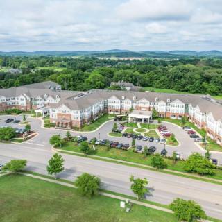 Aerial view of a residential complex surrounded by greenery and parking areas.