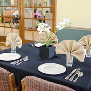 Elegantly set dining table with folded napkins and a floral centerpiece.