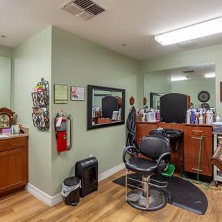 An interior view of a barbershop with a styling chair, mirrors, and hair care products.