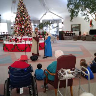 A festive Christmas performance with children captivated by the scene in front of a beautifully decorated tree.