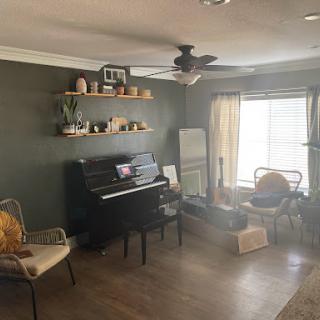 A cozy living room featuring a black piano, stylish shelves with decorative items, and comfortable seating.