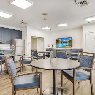 A modern dining and kitchen area with a round table, chairs, and a television.