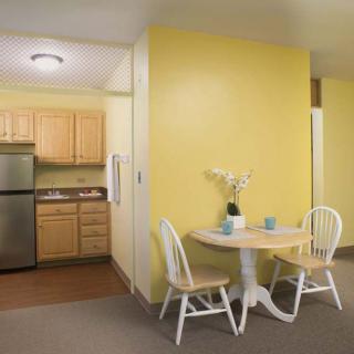 A cozy kitchen with a small dining area featuring yellow walls and wooden furniture.