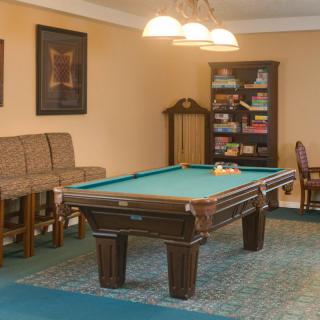 A cozy game room featuring a pool table, comfortable seating, and a well-stocked bookshelf.