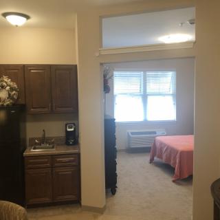 A cozy studio apartment with a small kitchen area and a bright bedroom.
