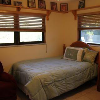 A cozy bedroom with a single bed and natural light filtering through wooden blinds.