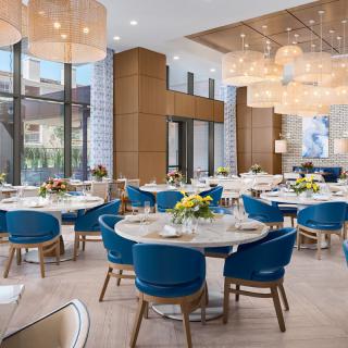 A modern restaurant dining area with elegant lighting and blue chairs.