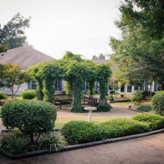 A peaceful garden with lush greenery and a pathway surrounded by trees and shrubs.