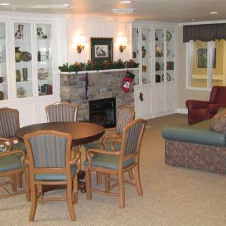 A cozy living room with a fireplace, surrounded by seating and a wooden dining table.