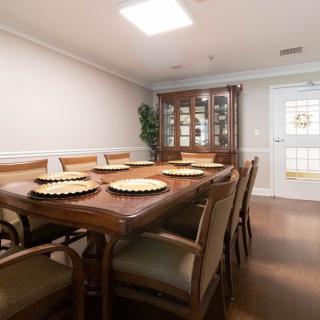 A well-appointed dining room featuring a large wooden table with chairs, a display cabinet, and placemats.