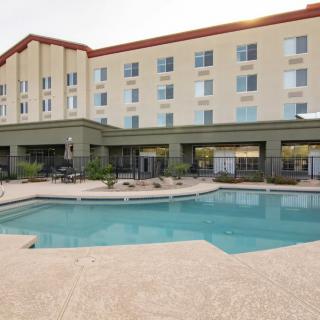 An outdoor pool area at a hotel with a multi-story building in the background.