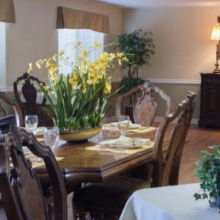 A beautifully decorated dining room with a wooden table and chairs, adorned with fresh flowers and plants.
