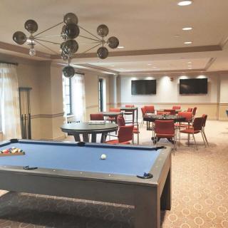 A modern game room featuring a pool table, multiple TVs, and comfortable seating.
