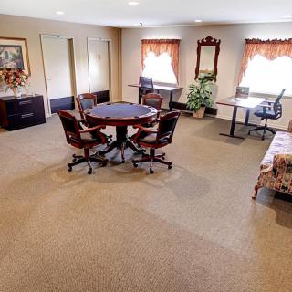 A well-furnished office space featuring a round meeting table, desks, and various chairs.