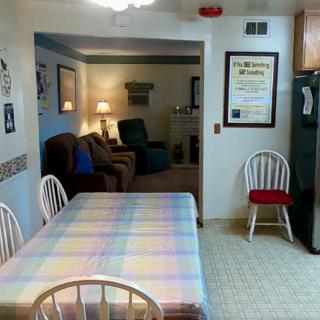 A cozy home interior featuring a dining area with a table and chairs, leading into a living room.